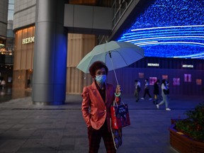 A woman wearing a face mask walks outside a shopping mall in Wuhan in China's central Hubei province on April 18, 2020.