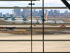 Parked WestJet planes are seen through the windows of the Calgary International airport which was almost deserted amid the COVID-19 pandemic on Wednesday, April 29, 2020.  Gavin Young/Postmedia