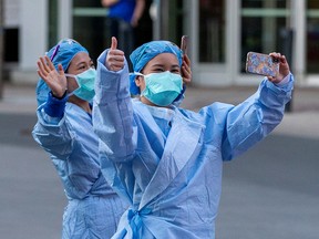 Health care workers wave as Toronto police and the city's front-line responders pay tribute to them along University Avenue on Sunday, April 11, 2020.