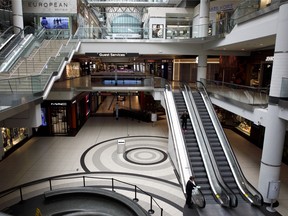 A shopper rides an escalator in the nearly empty Toronto Eaton Centre on March 25, 2020.