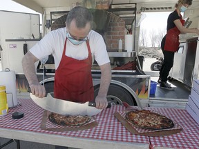 Jim, Owner of Il Forno Vagabondo Wood Fired Pizza, is seen preparing a fresh pizza as several vehicles line up in the Southcentre Mall parking lot for a food truck drive thru experience hosted by YYCFoodTrucks. Customers were served in their vehicles while practising physical distancing during the COVID-19 Pandemic. It was the first YYCFoodTruck event of 2020. Sunday, April 19, 2020. Brendan Miller/Postmedia