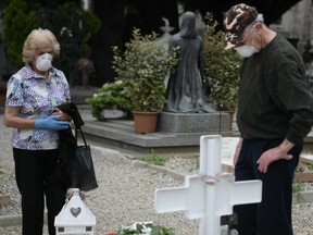 People pray next to the tomb of a relative at the Monumental Cemetery of Bergamo, Lombardy, a day after it reopened on May 19, 2020 as the country's is easing its lockdown aimed at curbing the spread of the COVID-19 infection, caused by the novel coronavirus.