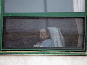 A resident looks out her window at Residence Herron, a senior's long-term care facility, following a number of COVID-19 deaths in the suburb of Dorval in Montreal on April 13, 2020.