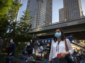 Commuters wearing face masks to protect against the new coronavirus walk through the central business district in Beijing, Tuesday, May 19, 2020.
