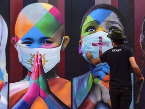 Brazilian mural artist Eduardo Kobra works on his recent work "Coexistence" -which shows children wearing face masks due to COVID-19 in Itu, Brazil. (Photo by Nelson Almeida / AFP)