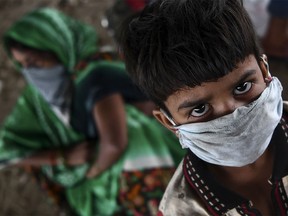 A young child from a migrant workers family waits for transport with others to return to their hometowns in Uttar Pradesh and Bihar states after police stopped them from crossing the Delhi-Uttar Pradesh border on foot as the government eased a nationwide lockdown as a preventive measure against the COVID-19 coronavirus, in New Delhi on May 17, 2020.