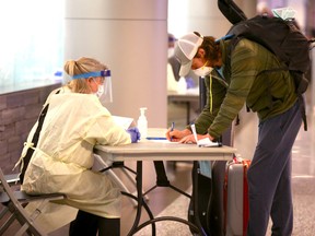 Alberta Health Services staff screen passengers entering the arrivals area at the Calgary International Airport on Wednesday, May 20, 2020.