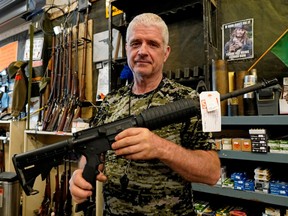 Jim Osadczuk, owner of a gunshop named Sebarms Guns and Gear, holds an AR-15 variant rifle at his shop in Edmonton on May 2, 2020. The government of Canada is banning this type of military-style assault weapon in Canada.