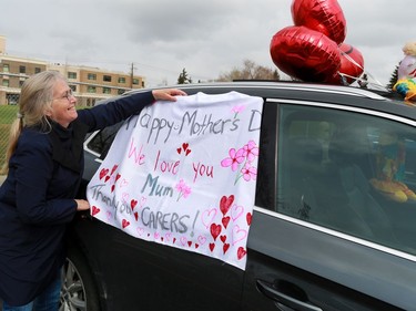 Jill Teschke attaches a sign for her mom as part of a MotherÕs Day parade of cars for the momÕs and grandmothers at the Amica Britannia seniors residence in Calgary on Sunday, May 10, 2020.   Gavin Young/Postmedia