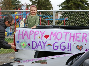 Greg Rutherford and his daughter Grace attach a banner for GraceÕs grandmother as part of a MotherÕs Day parade of cars for the momÕs and grandmothers at the Amica Britannia seniors residence in Calgary on Sunday, May 10, 2020.   Gavin Young/Postmedia
