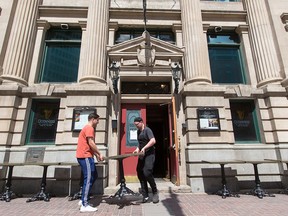 James Joyce Irish Pub staff Liam McLaughlan, left and Connor O'Hare move patio tables out onto Stephen Avenue Mall in downtown Calgary on May 13, 2020.