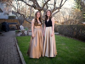 Twin sisters Jane and Claire Hopkins pose in their graduation dresses in their Calgary backyard on May 14, 2020. They are graduating from Henry Wise Wood High School this year but there will be no large ceremonies due to COVID-19.
