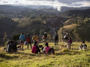 CP-Web.  Venezuelan migrants look out from a grassy knoll at the Panamericana Highway, in Urbina, Ecuador, on August 27, 2019. The ripples from Venezuela's collapse are shifting Canada's Western Hemisphere neighbourhood, creating major long-term costs for the new Liberal minority government. South America's borders remain the same, but the outflow of more than 4.5 million Venezuelan refugees in other countries is predicted to grow to more than six million by the end of 2020, according to new estimates from the United Nations refugee agency. That's nearly one in five Venezuelans.