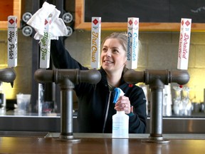 Mallory Welechenko, the Marketing & Brand Manager for Trolley 5, cleans some of the taps in the upper atrium area at the location on 17 Ave SW in Calgary on Friday, May 1, 2020. Jim Wells/Postmedia