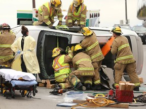 Calgary firefighters work to free a man from a car after a rollover accident at northbound 14 St and Glenmore Tr SW in Calgary on Sunday, May 3, 2020.