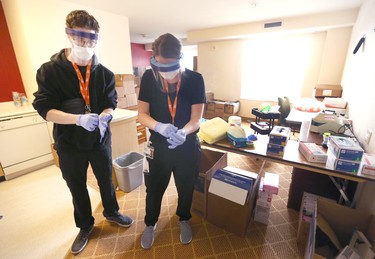 Nurses Keel Stewart (L) and Emma Wissink put on safety gear as they prepare to deliver medication at the assisted self isolation hotel in Calgary on Thursday, May 7, 2020. Postmedia has agreed not to reveal the exact location of the hotel. Jim Wells/Postmedia