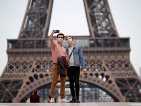 People wearing face masks take a selfie at Trocadero square near the Eiffel Tower, as France began a gradual end to a nationwide lockdown due to the coronavirus disease (COVID-19) in Paris, France, May 16, 2020.