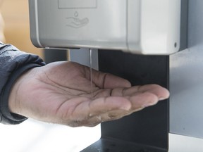 A man dispenses hand sanitizer in a shopping mall in the Montreal borough of Pointe-Claire, Saturday, March 14, 2020, as COVID-19 cases rise in Canada and around the world. Doctors at Alberta Health Services say people using hand sanitizer when they are out shouldn't leave it in their car for too long because it could lead to a fire.