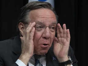 Quebec Premier Francois Legault shows off the glasses he now wears, during a news conference on the COVID-19 pandemic, Wednesday, May 13, 2020 at the legislature in Quebec City.