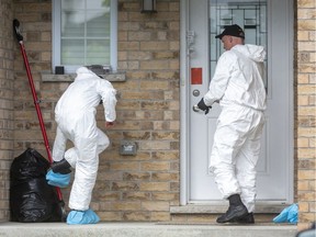 A note from a neighbour remains taped to the front door of the house at 39 Leesboro Trail in Thorndale northeast of London, Ont. as two tyvek suited forensic identification officers get ready to enter the house. OPP have been on the scene, where a body was found, since Tuesday.