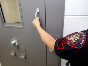 A Calgary police officer clasps the handle of a door at the CPS's arrest processing unit in the city's northwest in May, 2020.