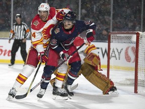 Calgary Flames' Travis Hamonic checks Winnipeg Jets' Mathieu Perreault in front of goalie goaltender David Rittich during the NHL Heritage Classic at Mosaic Stadium in Regina on Oct. 26, 2019. Troy Fleece/Postmedia Network