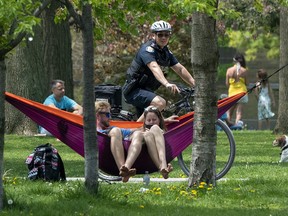 A police officer patrols Trinity Bellwoods Park in Toronto on Sunday, May 24, 2020. Warm weather and a reduction in COVID-19 restrictions has many looking to the outdoors for relief.