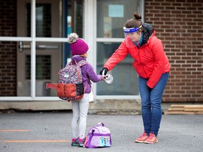 A student has her hands sanitized in the schoolyard, as schools outside the greater Montreal region begin to reopen amid the COVID-19 outbreak, in Saint-Jean-sur-Richelieu, Que., on May 11, 2020.