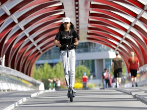 A woman crosses the Peace Bridge on an e-scooter on Aug. 1, 2019. The popular scooters are coming back to Calgary.