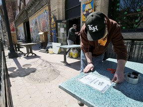 An employee at the King's Head Pub in Winnipeg prepares a patio for patrons. Calgary should allow the expansion of patios, even on to streets, during the better weather to help establishments get back on their feet, says columnist Rob Breakenridge.