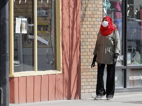 A pedestrian wearing a mask is seen walking along 10th St. NW during the COVID-19 pandemic in Calgary.