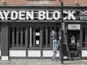 Richard Schnurr is seen cleaning windows at Hayden Block Smoke & Whiskey barbecue restaurant along Kensington Rd. NW. Many businesses are in anticipation of Phase One of the provincial strategy to open some parts of the province, which awaits approval, during the COVID-19 pandemic in Calgary. Tuesday, May 12, 2020.