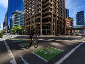 A cyclist crosses the 8 Ave. S.W. in downtown Calgary as the light reflected from the Husky buildings has covered the intersection on Wednesday, June 10, 2020.