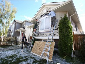 Residents start on repairs on a house on Saddlemead Rd NE in Calgary on Sunday, June 14, 2020. A severe storm ripped through Calgary shredding homes and cars.