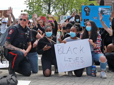 A Calgary police officer kneels in solidarity with several thousand Calgarians participating in an anti-racist rally in downtown Calgary on Monday, June 1, 2020. The protesters were also lying down the way George Floyd, 46 was when he was killed by a police officer in Minneapolis, Minnesota. That Minneapolis officer has since been charged with murder. Gavin Young/Postmedia