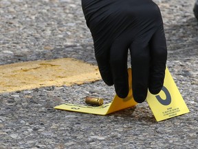 Calgary police place an evidence marker at a bullet casing after gunshots were fired in a parking lot at Marlborough Mall in Calgary on Saturday, June 20, 2020.