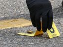 Calgary police place an evidence marker at a bullet casing after gunshots were fired in a parking lot at Marlborough Mall in Calgary on Saturday, June 20, 2020. 