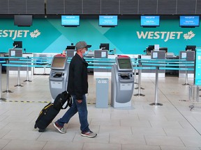 A passenger walks past a quiet WestJet check-in counter at the Calgary International Airport on Wednesday, June 24, 2020. WestJet announced Wednesday the layoff of 3333 employees in the continuing fallout from the COVID-19 pandemic.