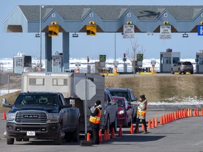 Provincial health department workers stop traffic that has crossed the Confederation Bridge in Borden-Carleton, P.E.I., March 22, 2020.