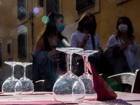 Women wearing face masks walk past a terrace of a restaurant in Trastevere in central Rome on June 5, 2020, as bars and restaurant reopened after months-long closures aimed at stemming the spread of COVID-19.