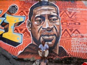 A man sits under a graffiti depicting African-American man George Floyd, who died in Minneapolis police custody, at the Kibera slum of Nairobi, Kenya, June 4,2020.