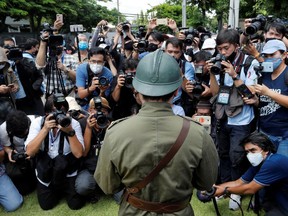 Members of the media take a photo of a protester dressed in a vintage uniform during a demonstration to demand for change in the constitution on the 88th anniversary of a revolt that ended absolute monarchy in the country, in front of parliament building in Bangkok, Thailand, June 24, 2020.