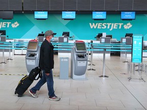 A passenger walks past a quiet WestJet check-in counter at the Calgary International Airport on Wednesday, June 24, 2020.