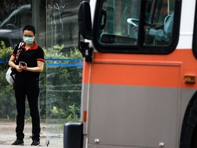 A person wearing a mask waits for the bus in downtown Calgary on Monday, July 13, 2020.