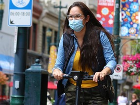 An e-scooter rider wears a mask as she cruises along Stephen Avenue in Calgary on Wednesday, July 15, 2020.