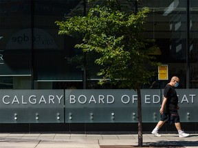 A pedestrian walks in front of the Calgary Board of Education headquarters on Tuesday, August 4, 2020.
