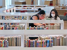 Elise Ferraro and her daughter Claire wear masks as they browse for books in the Central Library on Monday, July 27, 2020. Masks in all public indoor buildings will be mandatory under a new bylaw starting on August 1.