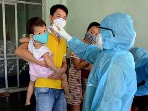 A health worker gets the temperature of residents at the area of a newly found coronavirus infected patient in Da Nang city, Vietnam July 26, 2020.
