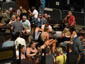 People sit with drinks at outdoor seating at a pub in the centre of Manchester, northwest England, on July 31, 2020. - Britain on Friday "put the brakes on" easing lockdown measures and imposed new rules on millions of households in northern England, following concerns over a spike in coronavirus infections.