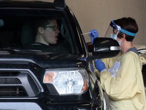 A driver is tested for COVID-19 in one of the drive-through testing centres at the Richmond Road Diagnostic and Treatment Centre in Calgary on Thursday, July 9, 2020.